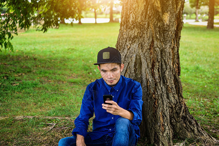 电话蓝衬衫人使用智能手机上网各地的科技社交媒体及自然背景阳光在网络上使用智能手机到处公司的图片