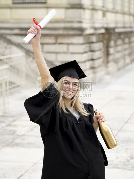 自豪的身着毕业礼服笑女青年子文凭吸引人的图片