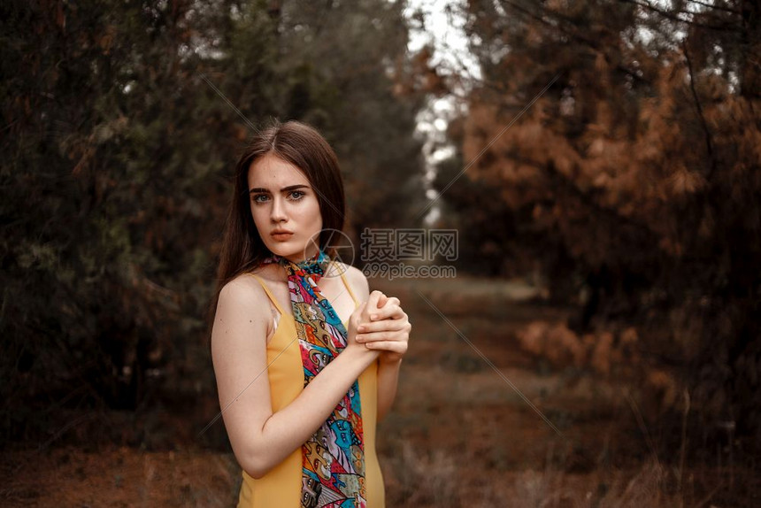 黄色的模型一个年轻美丽的女孩肖像身着黄色洋装带彩多的围巾站在树林里漂亮的图片