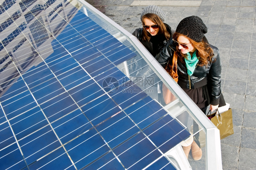 关注驾驶光伏坐在太阳能拖拉机旁边的两名年轻女青图片