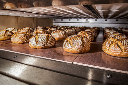 食物在一个多层电炉中对传统黑麦面包生产进行工业烘烤面包师持续的图片
