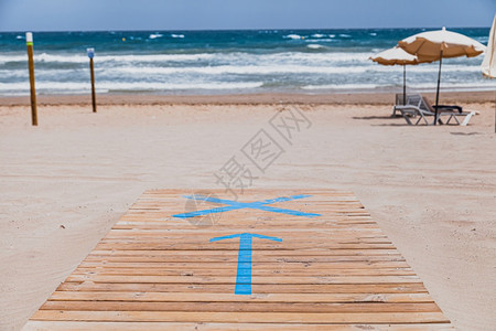 假期海岸线晴天指着滩入口处的木制行道上箭头标志物图片