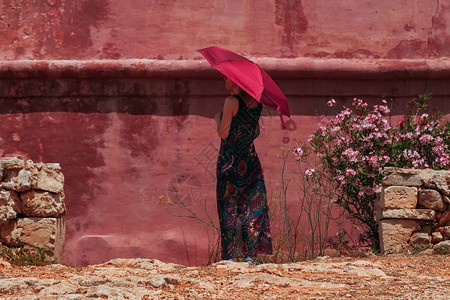 下一个可爱的年轻寂寞姑娘拿着红色雨伞保护自己免受太阳的照射就在红古城堡旁边淑女图片