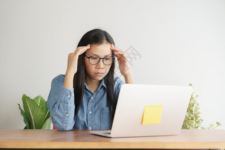 亚洲妇女长时间在电脑上工作的压力很大办公室综合症概念长期与计算机打交道的亚洲妇女痛桌子年轻的图片