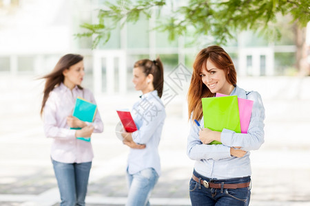 三位抱着书本的女学生走在校园里图片