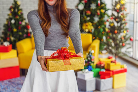 家迷人的十二月身穿彩色红毛衣戴帽子并将礼物盒送给他人用于庆祝圣诞快乐亚洲人或室内聚会Xma和新年概念亚裔或洲人室内派对Xmas和图片