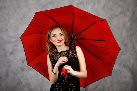 晚上美丽身着黑色晚礼服和红伞式雨的年轻姑娘身着红色伞式雨的年轻女士人们图片