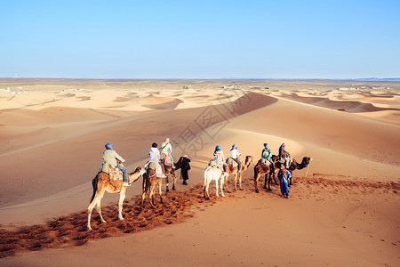 踪迹摩洛哥Merzouga市ErgShebbi撒哈拉沙漠地区享受骆驼大篷车的旅游者舍比假期图片