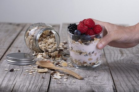谷物素食主义者水果手握麦杯配有酸奶和森林果实健康早餐概念图片