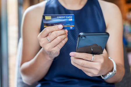 借方聪明的支付持有信用卡和使触摸屏智能手机在线购物同时咖啡店下订单生活方式技术电子商务和网上付款概念的青年临时商业妇女持信用卡和图片