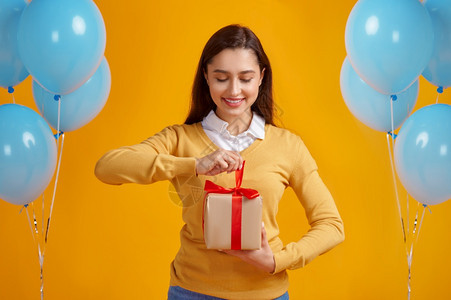 庆祝魅力快乐的女士打开礼物盒红丝带黄色背景漂亮女有惊喜事件或生日庆典气球装饰快乐的女士打开带有红丝的礼物盒吸引人图片