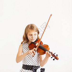 小提琴家美丽天才小女孩的肖像白种背景在小提琴机上玩耍的小提琴手肖像她是个美丽的天才小女孩学习漂亮的脸图片