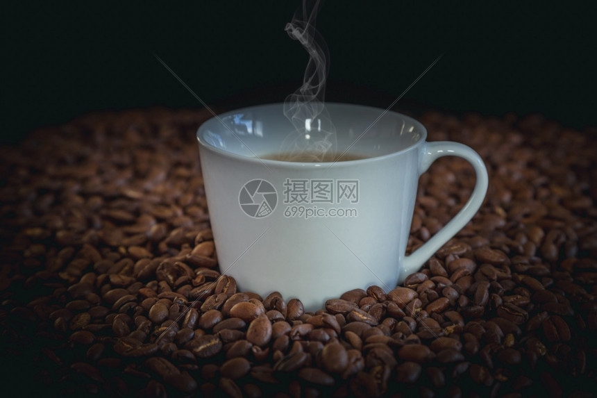 拿铁马克杯一个白色咖啡和许多豆的热加许多厅在温暖轻的气氛中以黑暗背景和复制空间将小木咖啡桶放在桌上喝图片