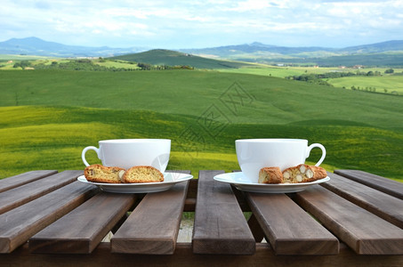 锡耶纳木制桌上的两个咖啡杯和罐子意大利托斯卡纳风景木制的杏仁图片