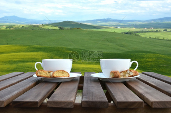 锡耶纳木制桌上的两个咖啡杯和罐子意大利托斯卡纳风景木制的杏仁图片