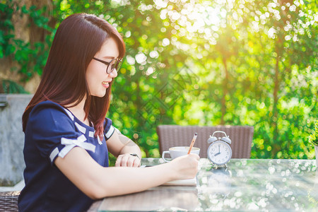 公司的美丽亚裔快乐年轻女商人在夏季公园工作记录一些做笔的东西女图片