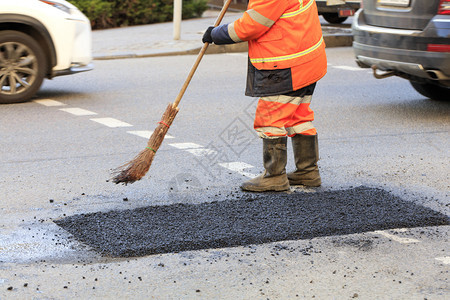 道路工人在修筑的段上用新鲜沥青扫一而出马路工人在修复的公路部分上用惊慌失措的方式收集新鲜沥青一名道路工人收集新鲜沥青存在一种新的图片