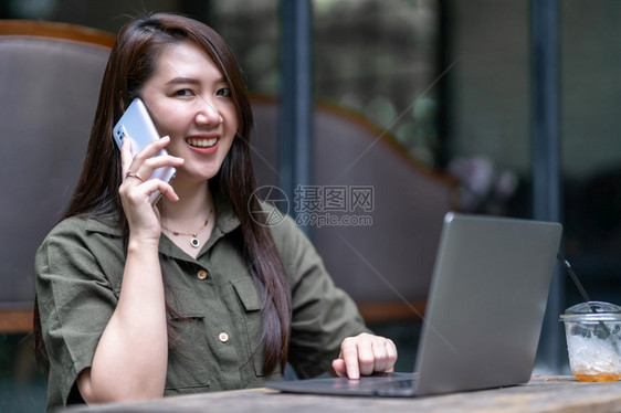 女商人在咖啡店用笔记本电脑工作时用咖啡杯和智能手机如背景通信概念等在咖啡店里捡起智能便携机的空闲手写作女士嗓音吸引人的图片