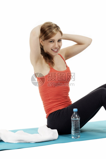运动型年轻快乐的健身女人在垫子上锻炼水放在一边年轻快乐的健身女人在垫子上锻炼水放在白色背景年轻的运动图片
