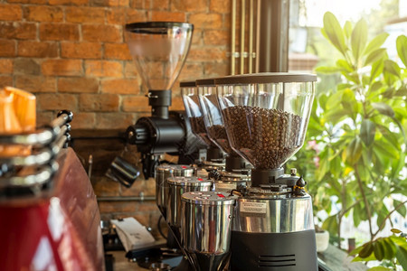 专业黑色电动研磨机和Espresso咖啡机紧贴于一家咖啡馆厅店的木制桌子上食物电的黑暗图片