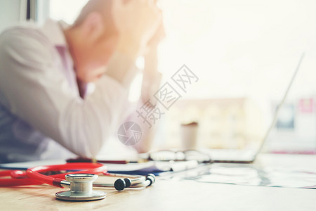 压力办公室亚洲人听诊镜和医生坐在笔记本电脑上头痛与在医院工作有关图片