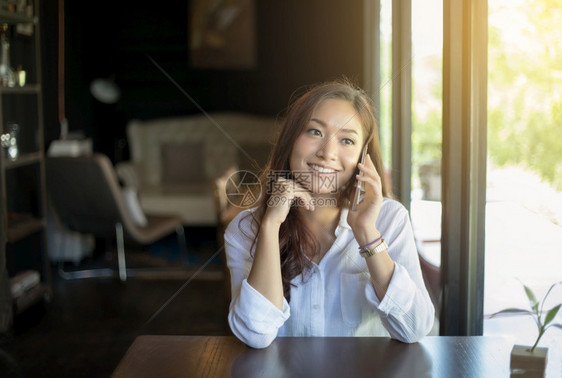 在空闲时间独自坐在咖啡店的里时用手机打电话的妇女和亚洲人沟通淑女潮图片