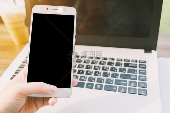 女士在咖啡店用空白黑屏的智能手机制作便记和笔文件本电脑之类的商业女企关闭工作键盘图片