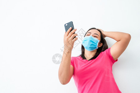 来电微笑在冠心病流行期间一名戴面罩的妇女使用智能手机的视频电话与朋友进行交流在冠心病行期间一名戴面罩的妇女淑背景图片