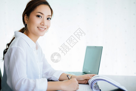 桌子美丽的医生使用笔记本的亚洲商业妇女为工作而笑高兴图片