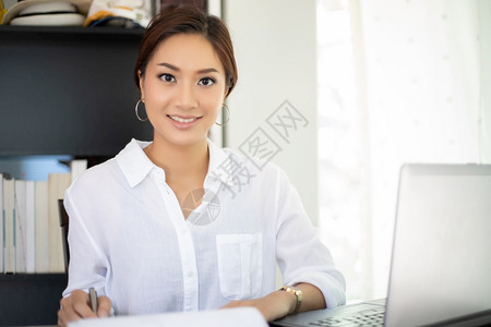 使用笔记本的亚洲商业妇女为工作而笑高兴办公室为了职业图片