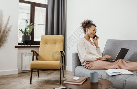 电脑白色的互联网坐在沙发上工作的妇女图片