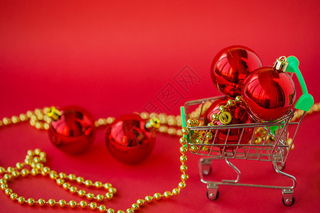 新的在微型手推车中赠送圣诞球和红色背景上的装饰品在线星期五图片