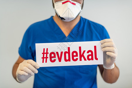 安全卡片一名医生纸上有evdekal土耳其语英译文留在家中手持铐保护人们免受科罗纳或Covid19流行病的感染呼吸图片