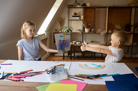 铅笔两个孩子在绘画课的餐桌上玩得开心孩子们在工作坊上艺术学校的课年轻画家愉快爱好乐童年两个孩子在绘画课的餐桌旁手调色板图片