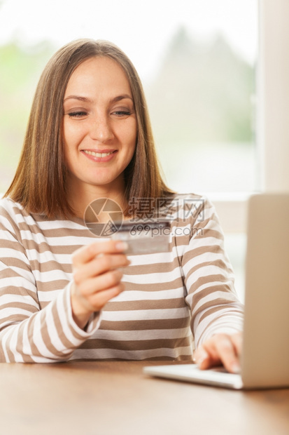 支付顾客在家网上购物时微笑着的年轻女士手里握着信用卡手持松弛图片