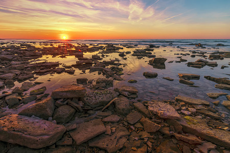 日落风景优美运动海面上丽的日出前面岩石很多图片