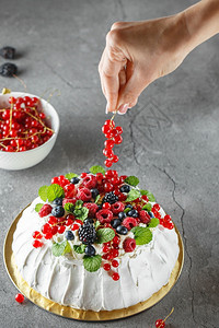 玫瑰Pavlova蛋糕加奶油和新鲜的夏天莓子关闭Pavlova甜点配有森林水果和薄荷食品摄影将蛋糕装饰过程用红卷饼果在照片上甜的图片