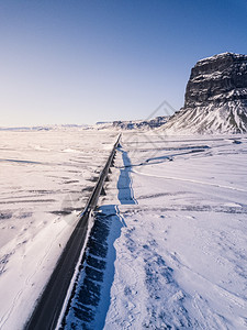 太阳蓝色的斯堪纳维亚语环形路1号在冰地的空中景象后面是洛马格努普山背景图片