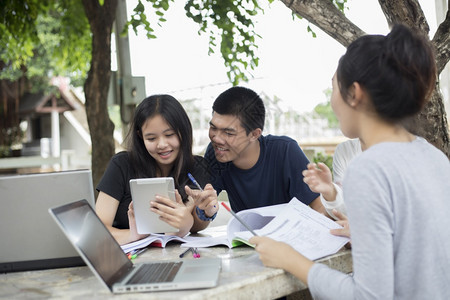 一起在户外看着电脑讨论的亚洲学生们图片