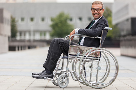 现代的友好肖像坐在轮椅上微笑的商人图片
