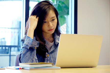在室内麻烦失败使用笔记本电脑工作在家临时办公室生活方式时有沮丧言论的年轻亚洲女青妇图片