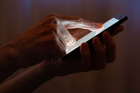 技术男子在靠近窗户的黑智能手机触摸屏幕上打字时用手指晚上闭着窗帘互联网图片