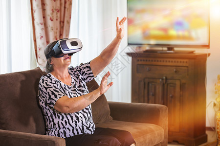 人们房间女士拥有虚拟头耳机或3D眼镜的高级妇女在家里玩视频游戏的家庭技术增强现实娱乐和人的概念以她手为焦点图片