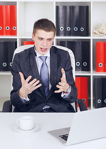 幸福年轻商人在办公室里拿着笔记本电脑的快乐青年商人白色的手势图片