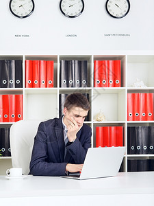有自信的青年商人在他办公室从事笔记本电脑工作英俊的担心企业家图片