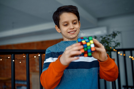 解决了微笑的男孩手里握着拼谜方块玩具用来进行大脑和逻辑思维训练创造游戏解决复杂问题微笑的男孩手里握着拼谜方块oopica图片