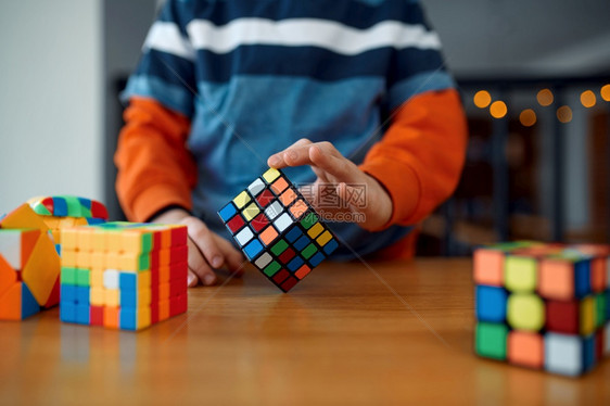 社论小男孩拿着拼谜方块有选择地关注手上的玩具用于大脑和逻辑心智训练创造游戏解决复杂问题男孩拿着解谜方块有选择地关注手边可图片