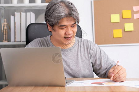 互联网打字在计算机上工作的笑亚洲商人注意到笔记本上的在家工作直到CoronaCOVID19隔离快乐自由职业者工作生活方式的概念电图片