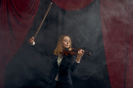 手持弓和小提琴的女紫罗兰用弦乐器音艺术在viola上演奏音乐剧的舞台女艺人独唱音乐会有深底背景的黑暗女弓和小提琴的紫罗兰舞者有首图片