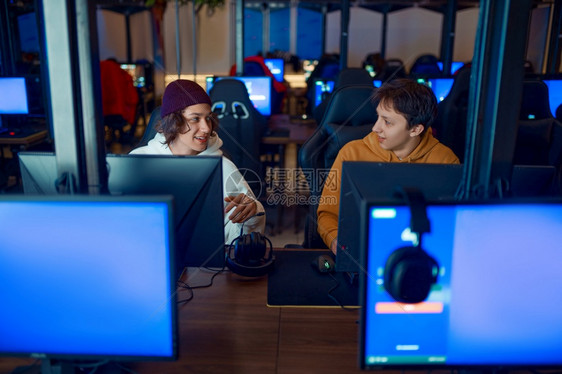 男生两个游戏玩家在俱乐部的电脑上玩虚拟娱乐电子竞技锦标赛网络运动生活方式男在网吧休闲两个游戏玩家在俱乐部的电脑上玩监视器比赛图片